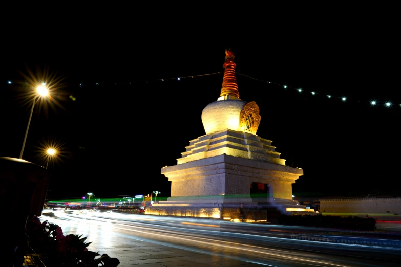 a lit - up pagoda at night along the street
