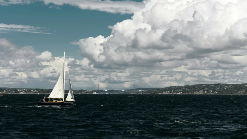 the sailboat is sailing through the waters near the shore