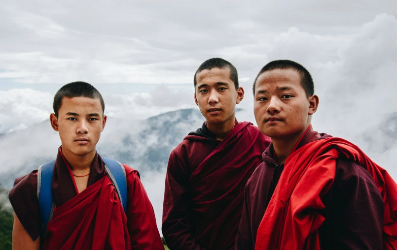 two men in red monk robes and an asian man