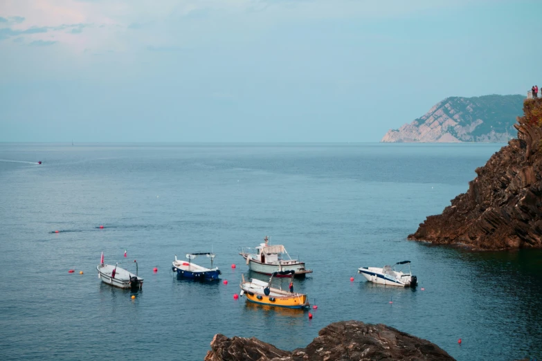 there are many boats on the water next to some rocks