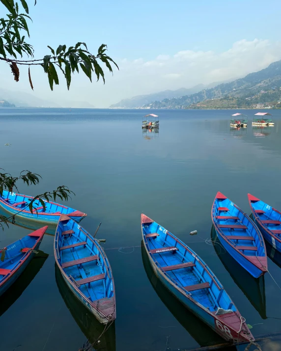 four row boats floating in water near mountains
