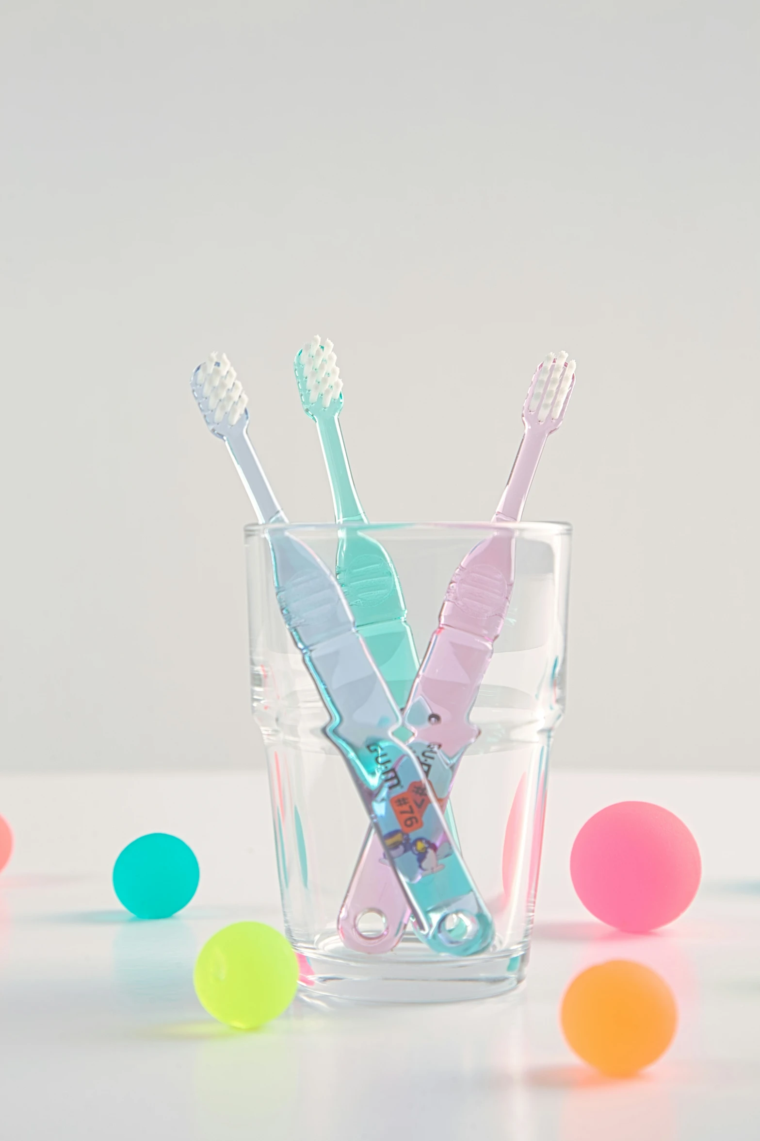 three tooth brushes sitting in a glass with bubbles on the side