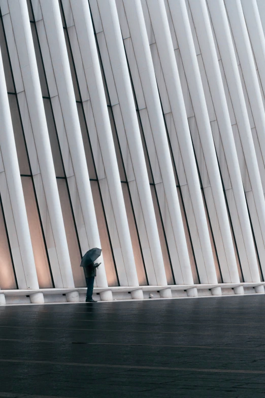 a man standing next to a white wall holding an umbrella