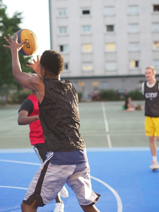 two boys playing basketball outside on the court