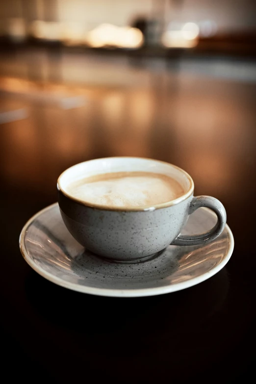 a white cup is on a plate near a bottle