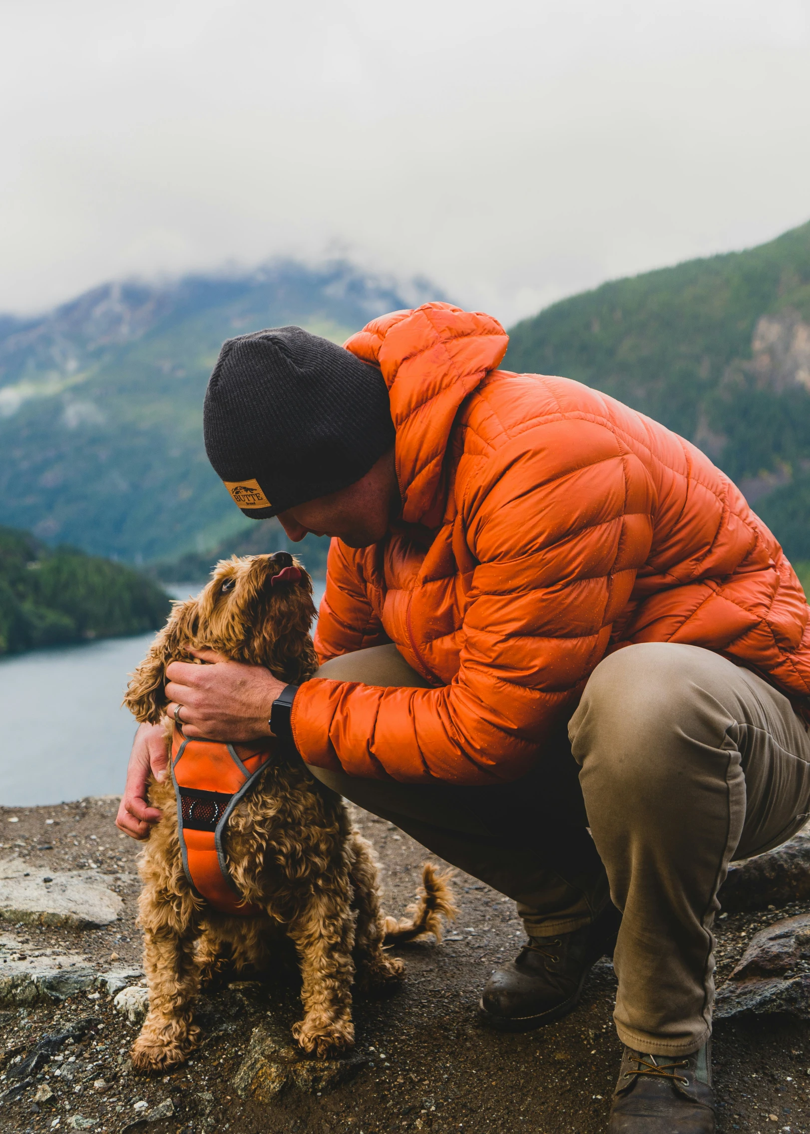 a man holding his dog while it looks down at the ground