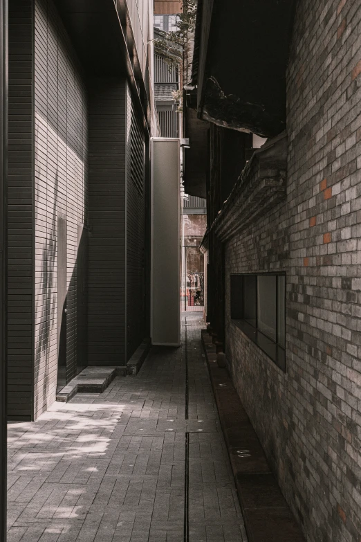 a narrow street that has a brick wall between it and a parking meter