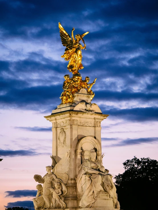 the sun is setting over the statue in the park