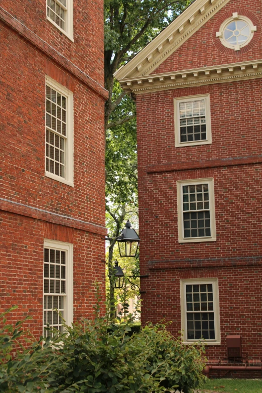 two tall red brick buildings side by side, one with a clock at the top