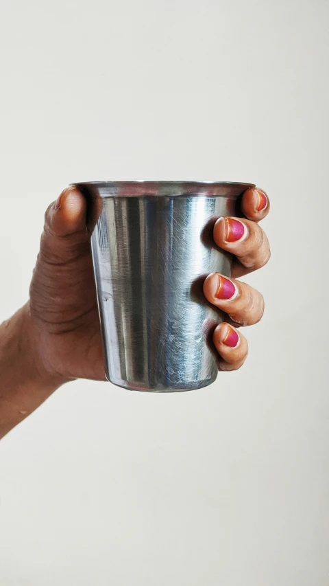 a woman holding a small metal cup in her hand