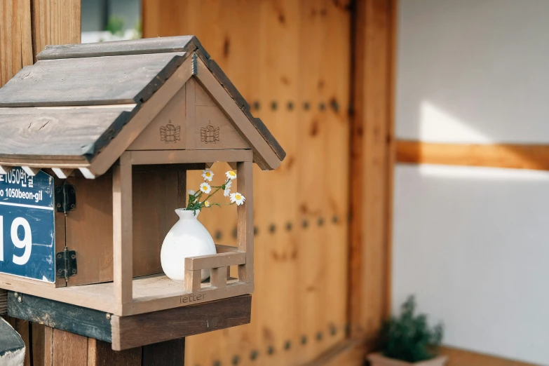 small wooden bird house holding flowers with number