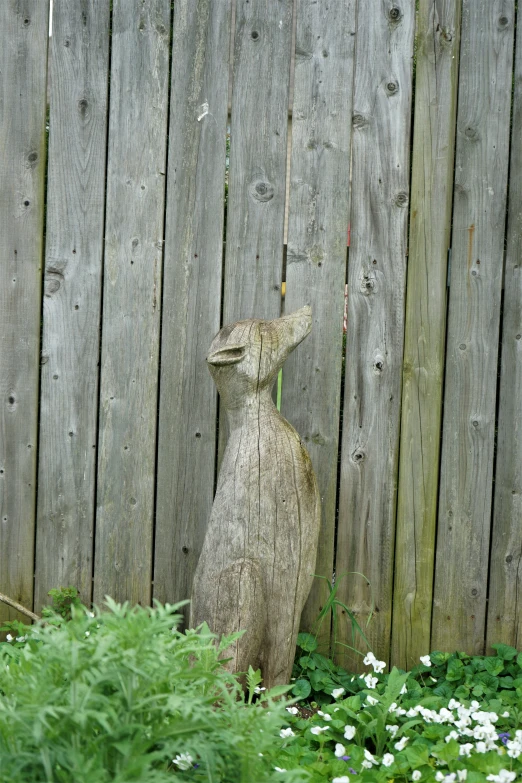 a small statue of a cat standing by a wooden fence