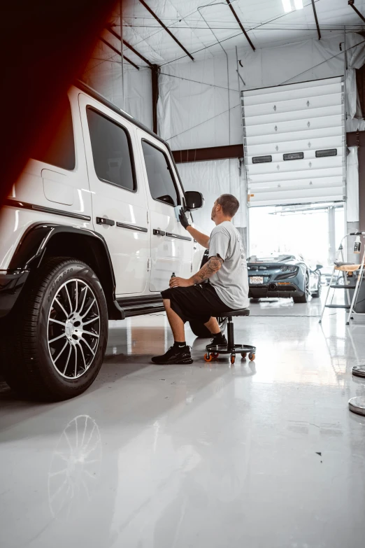 man painting a car on its rim in garage