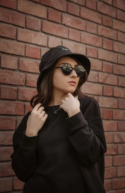 a woman standing next to a brick wall