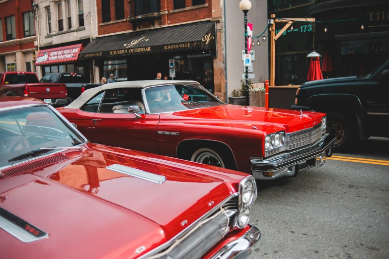 a row of old fashioned cars parked on the side of the street