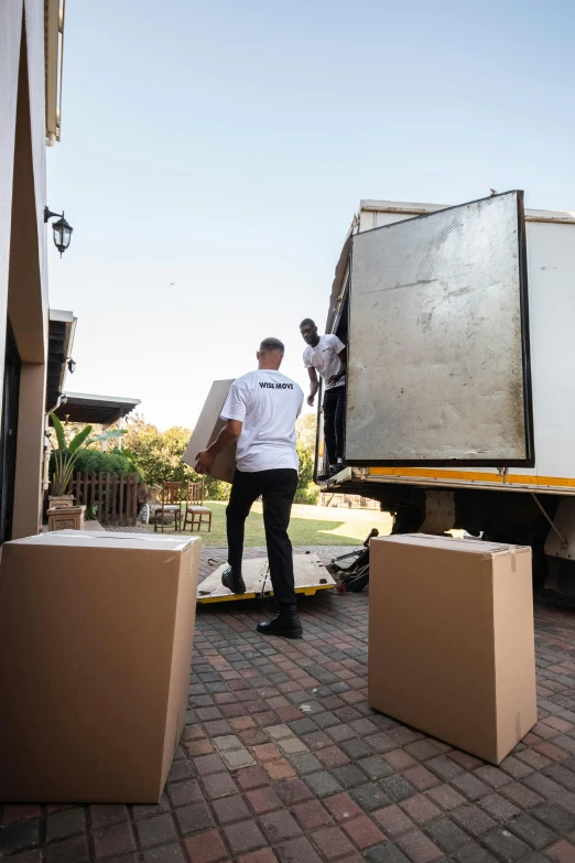 a man in white shirt loading up large packages on a truck