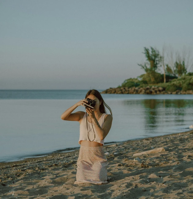 a person standing on a beach taking pictures with a camera