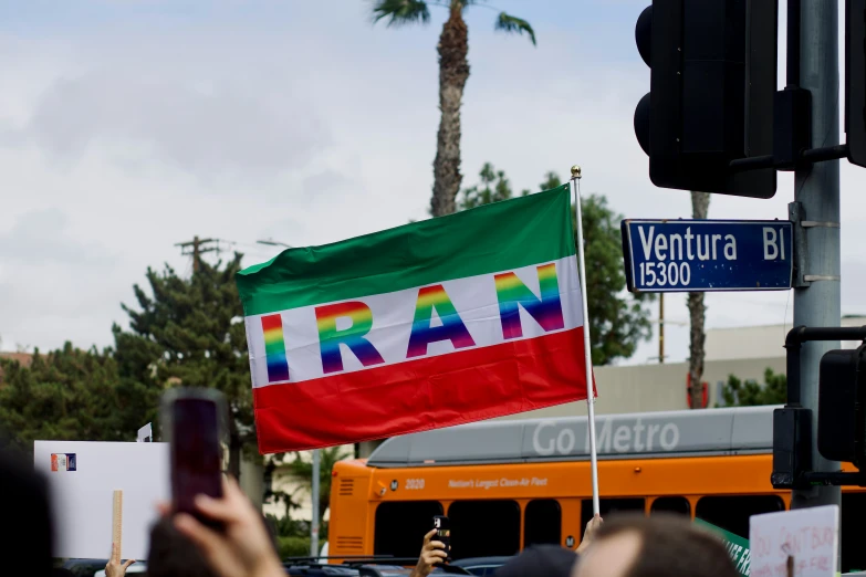 a person holding a phone standing in front of a flag