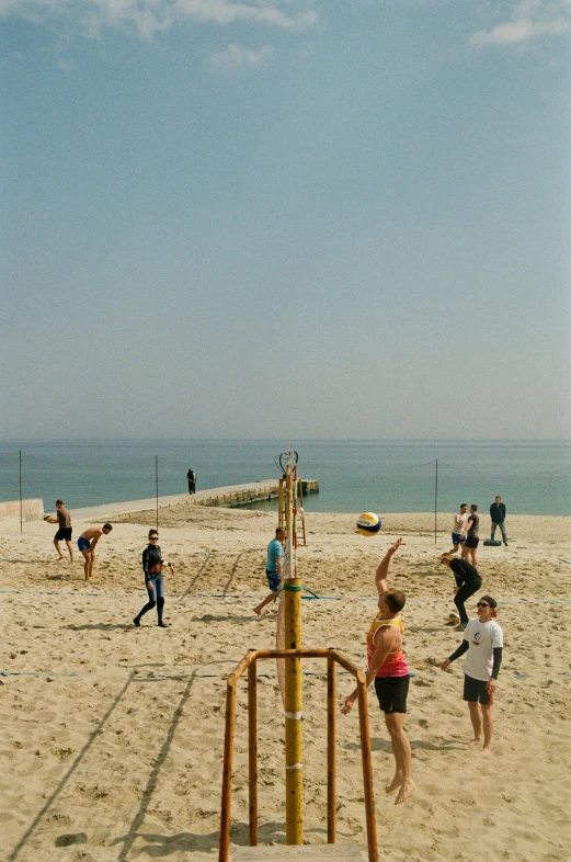 group of people playing volleyball on beach with water in background