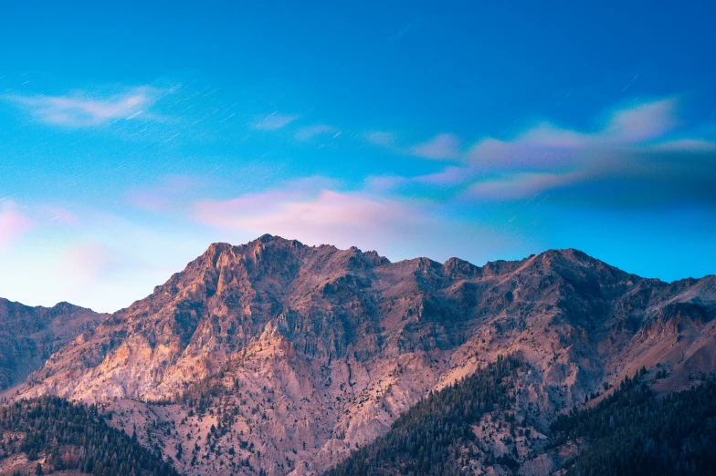 a blue sky with the light of an airplane over mountains