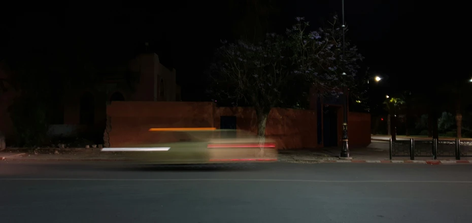 car light streaking down an urban street at night