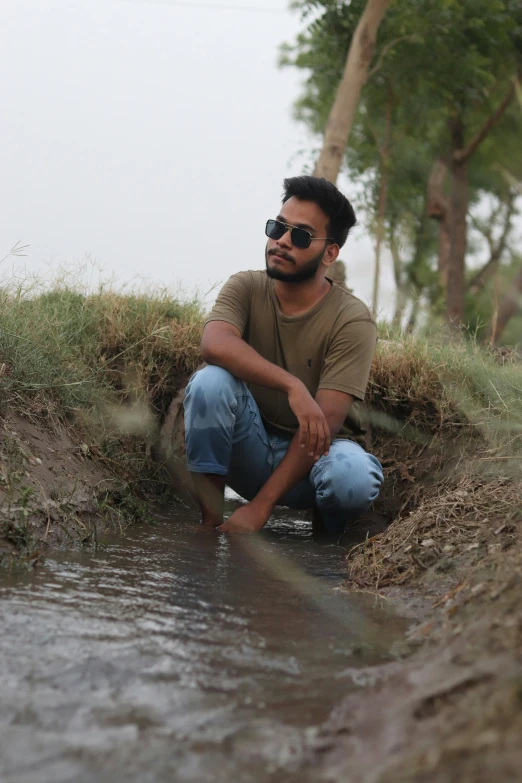 a man sits on a bank while squatting