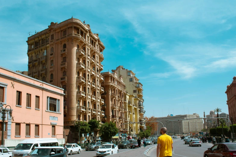 a man in yellow shirt walking down sidewalk by buildings