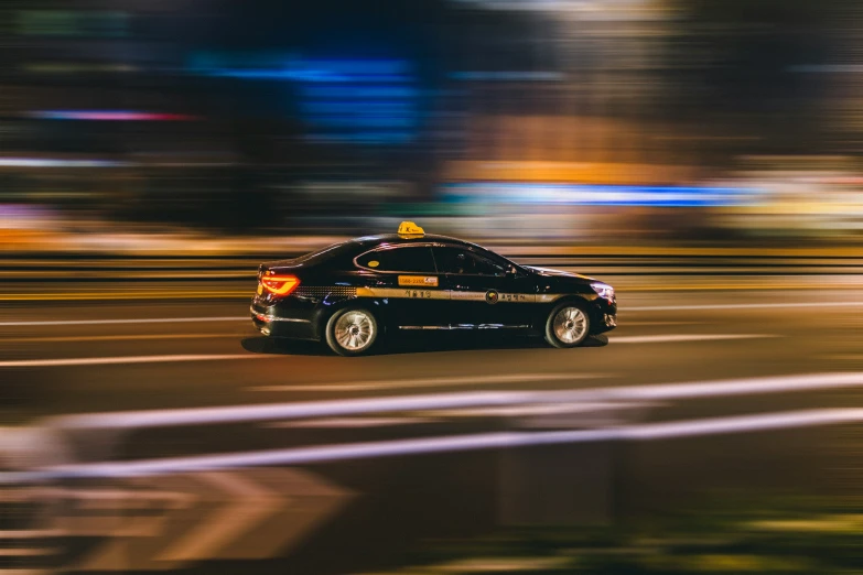 an orange and black car speeding in the street at night