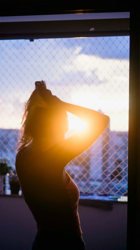 a woman is looking out of a window at the sun