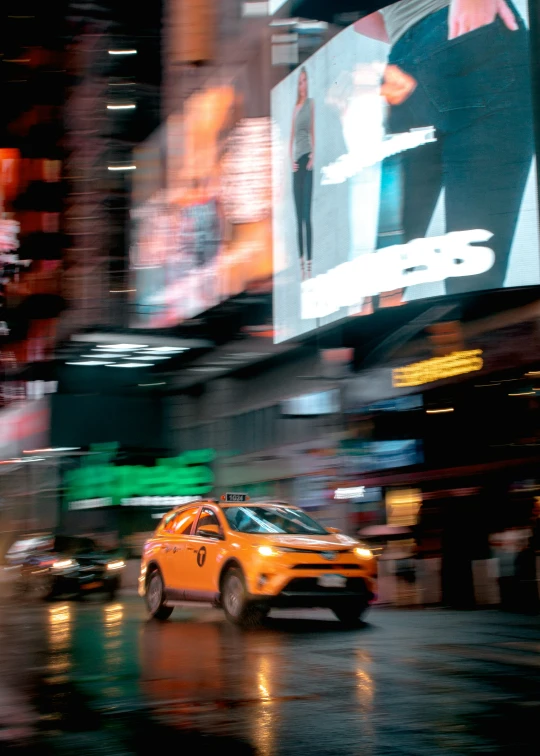 a taxi cab driving down a street next to tall buildings