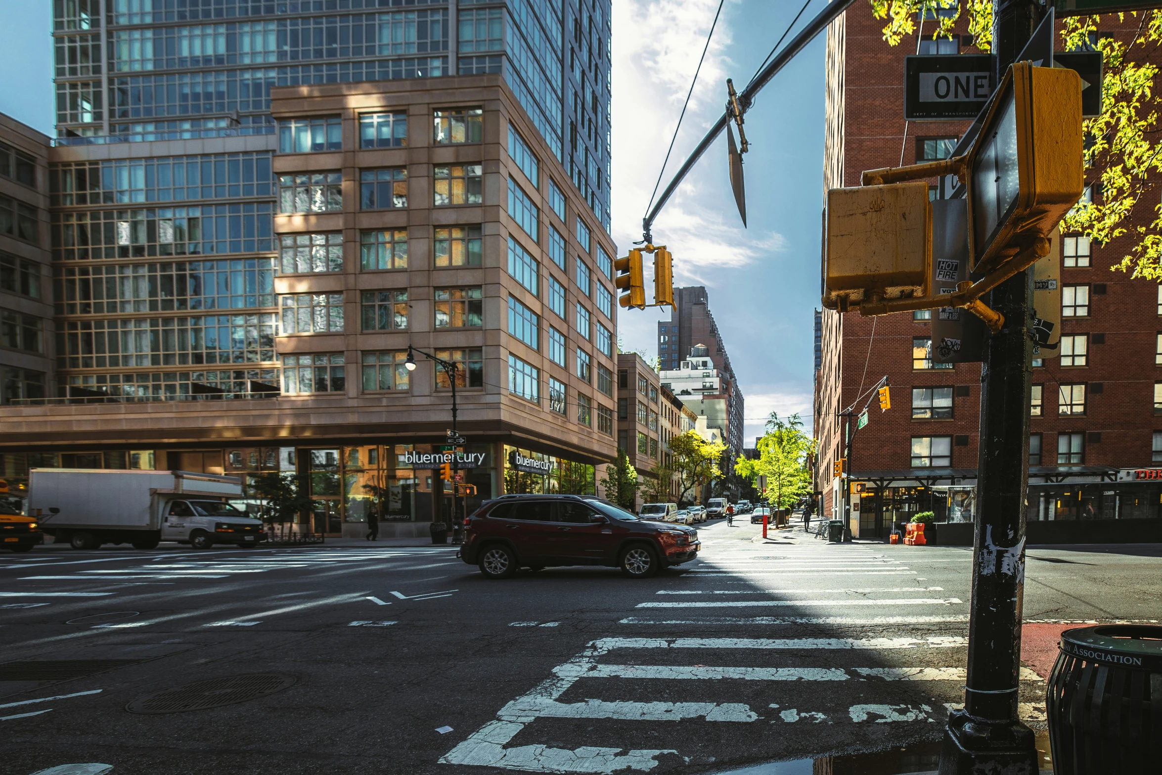 an intersection on the corner with a city traffic signal and a few cars waiting at an intersection