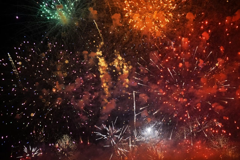 fireworks explode with bright green, red and orange lights