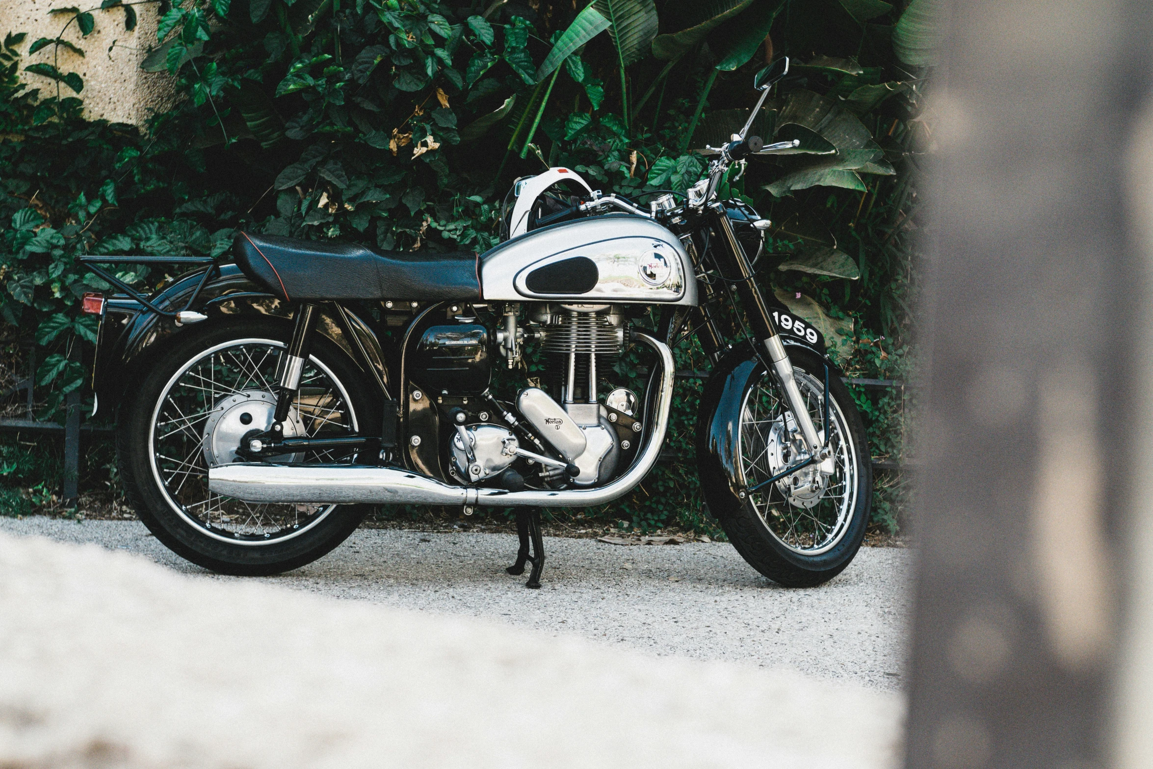 a motorcycle is parked near a bush and cement