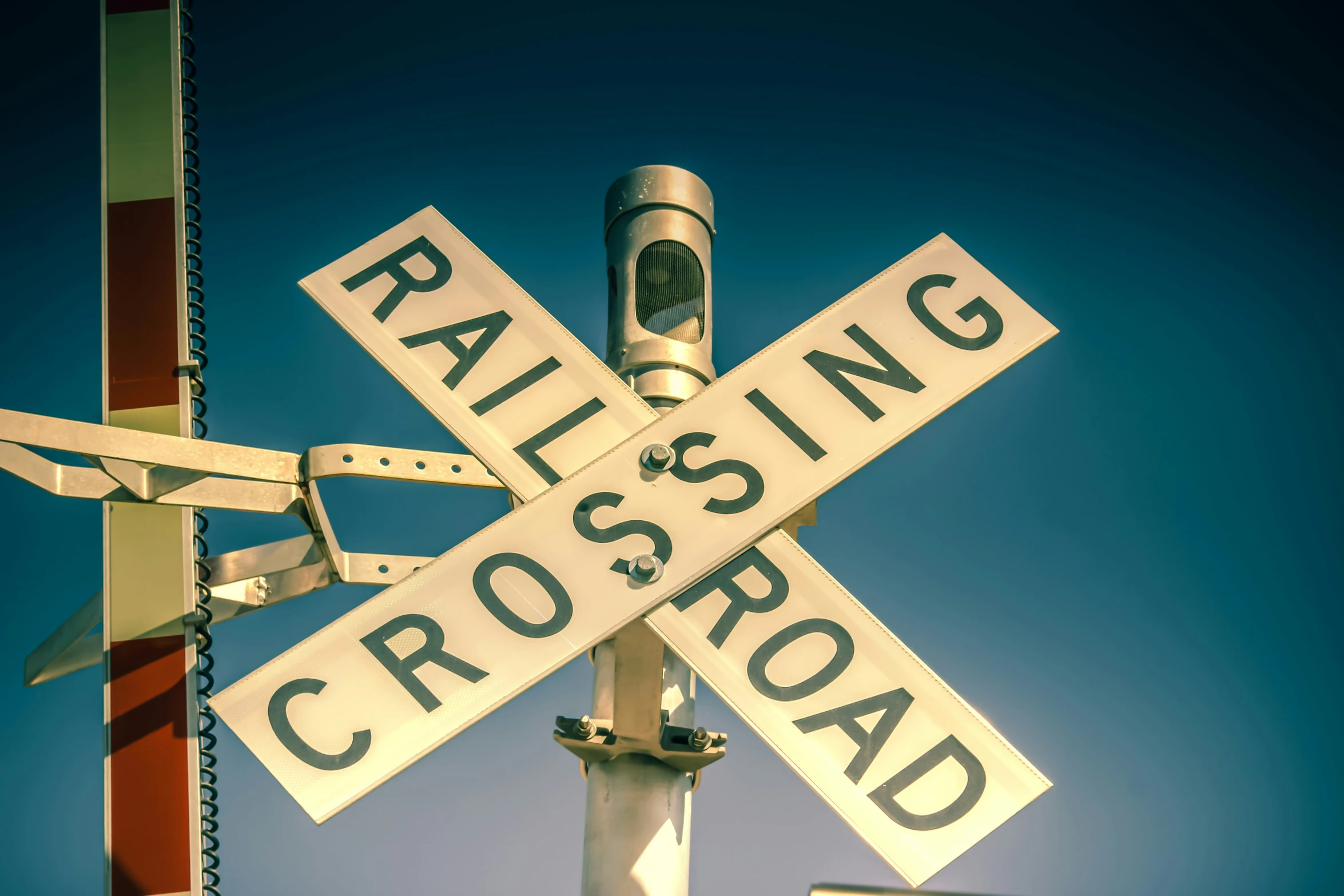 a railroad crossing sign under blue skies