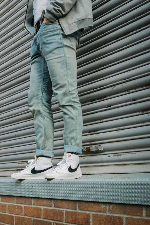 a person in jeans and sneakers standing on top of a brick wall