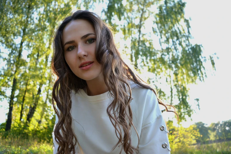 a beautiful young lady with long hair sitting in a park