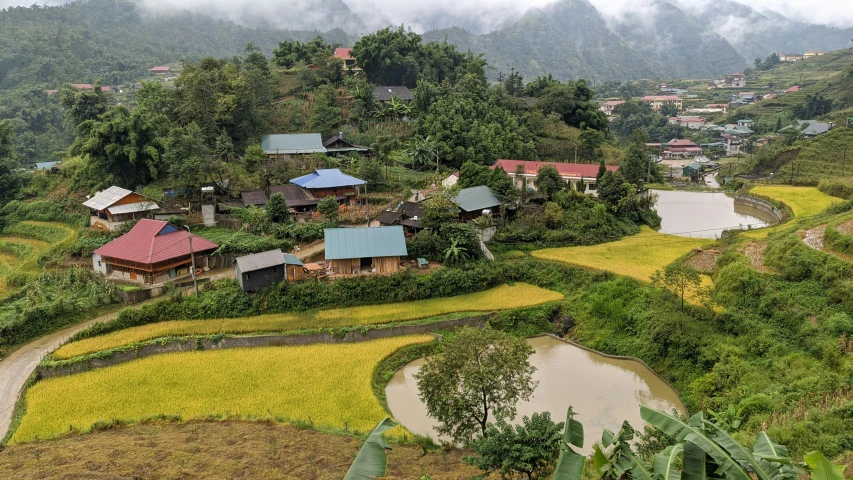 a hilly view of several huts surrounded by trees and mountains