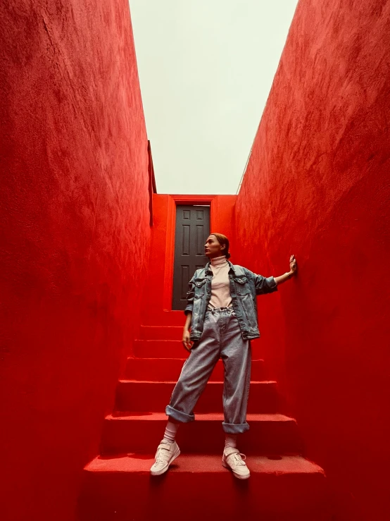 a woman standing on some stairs in front of a red wall