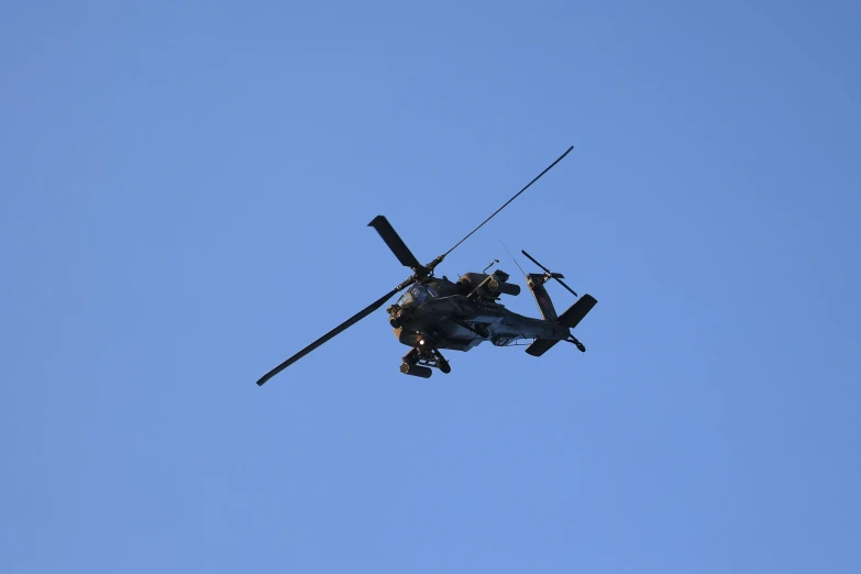 a military helicopter is flying through the sky