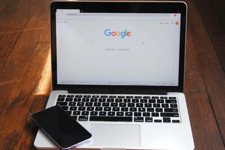 there is a cellphone next to a laptop on a table