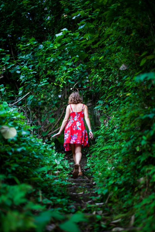 woman walking in woods on path surrounded by vegetation