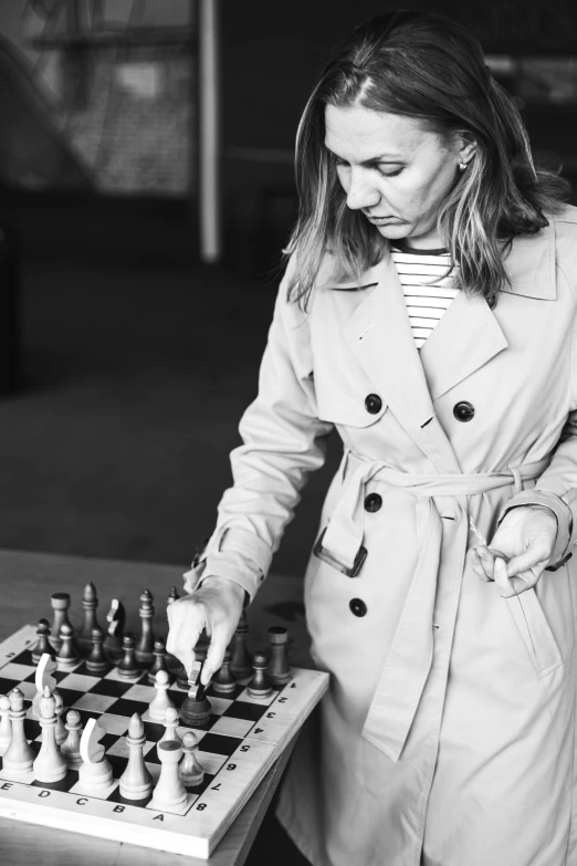 a woman in trench coat playing a game of chess