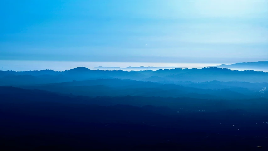 an airplane flying over the top of a very dark mountain range