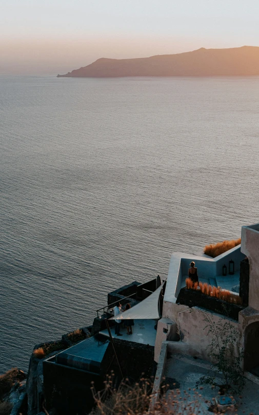 a small building overlooks the water and a cliff