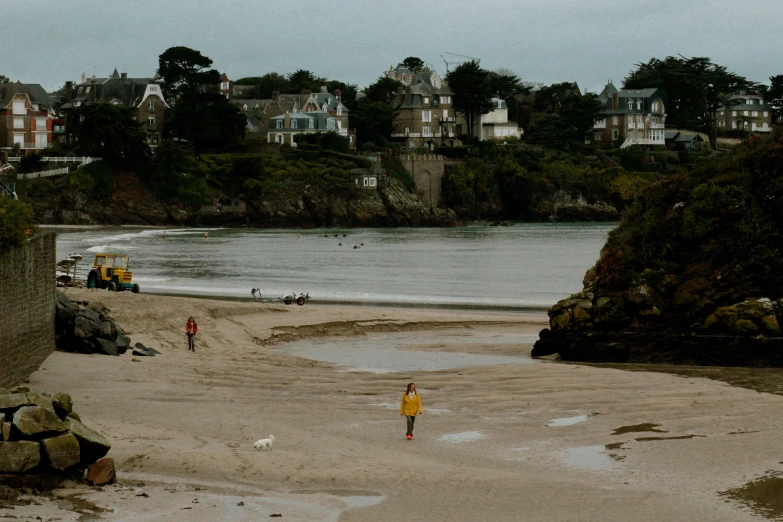 two people stand on a beach near the water