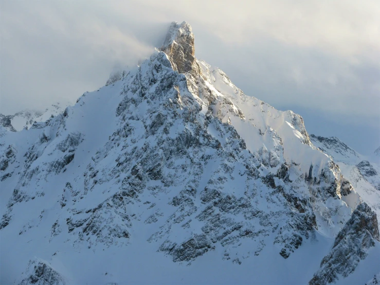 snow covered mountains sitting below a cloudy sky