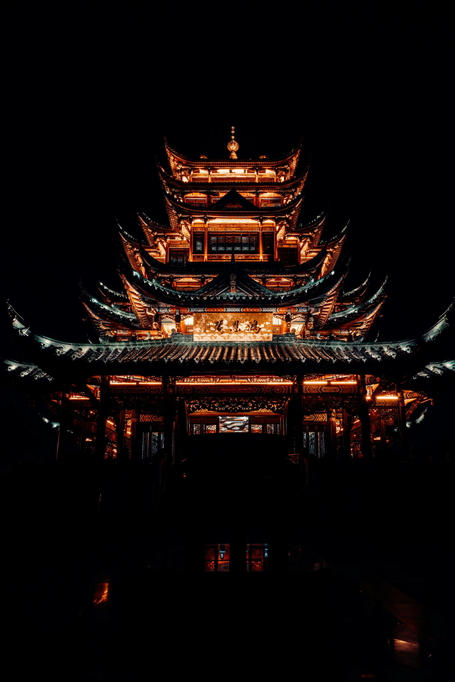 a tall asian building at night with lights