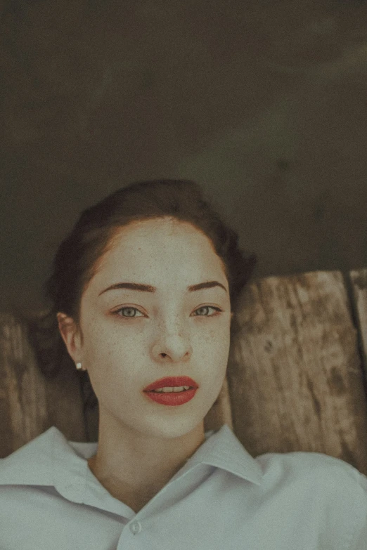 a woman with red lipstick sitting next to a wall