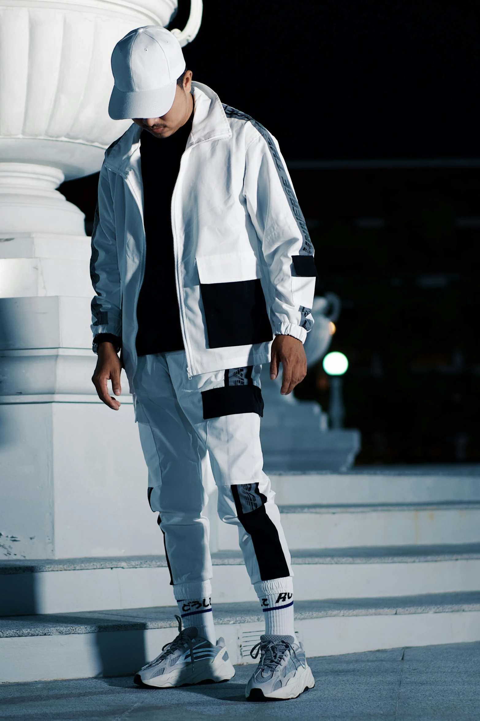 the young man wearing a hat and sports gear poses in front of a white pillar