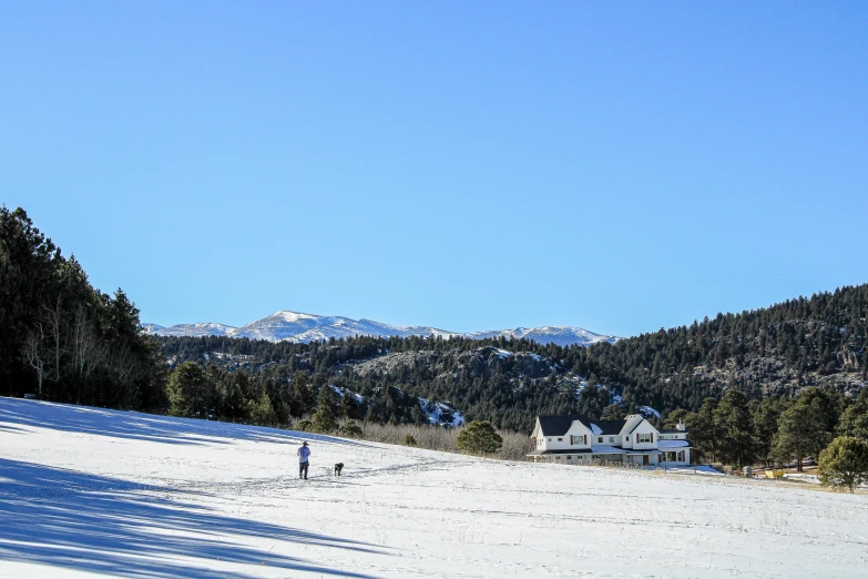 a view from the hill with two people walking on a snow covered hill